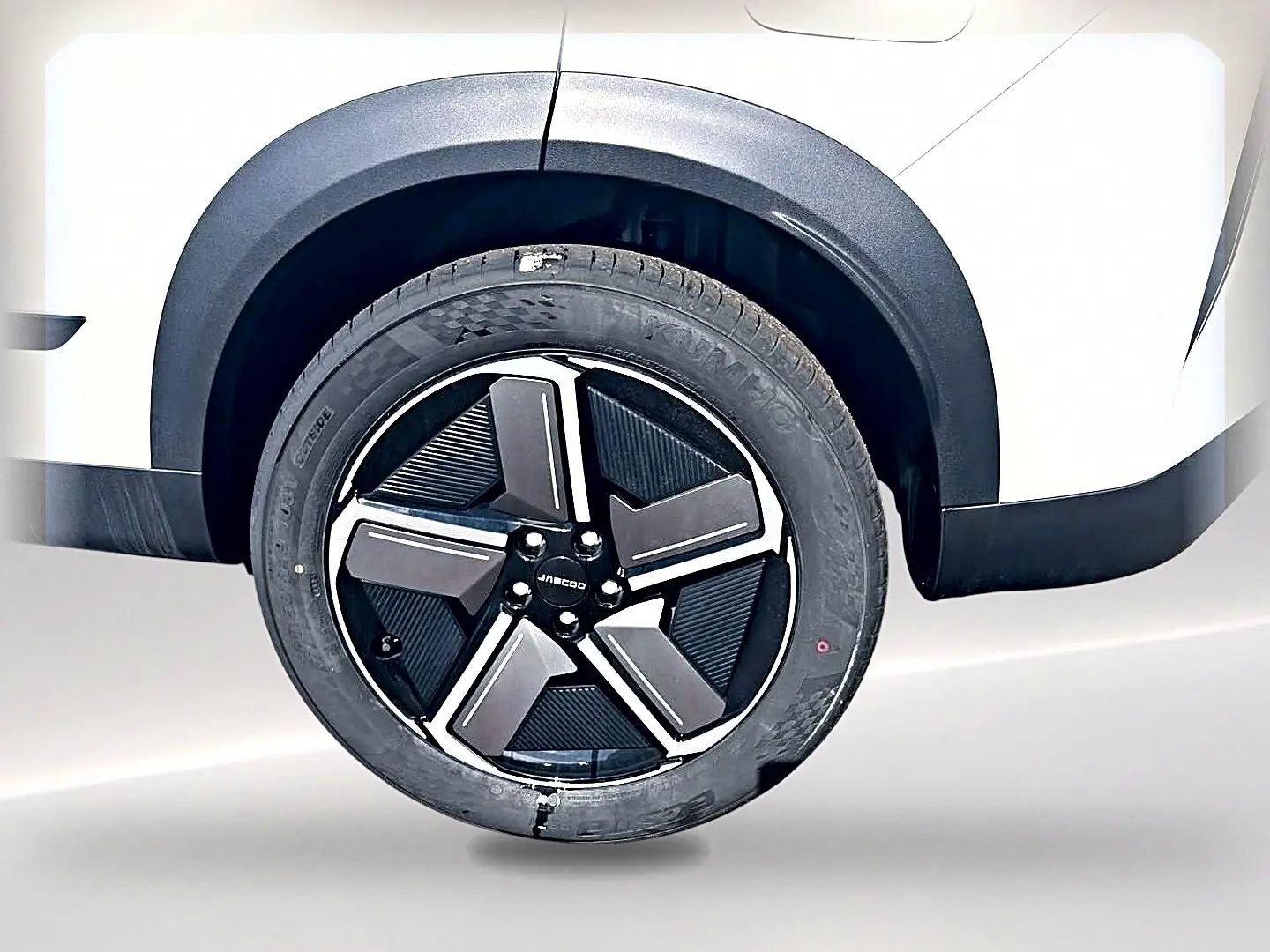Gros plan sur la roue arrière droite d’un JAECOO J7 blanc kaki avec jante alu noire et argentée au design moderne.