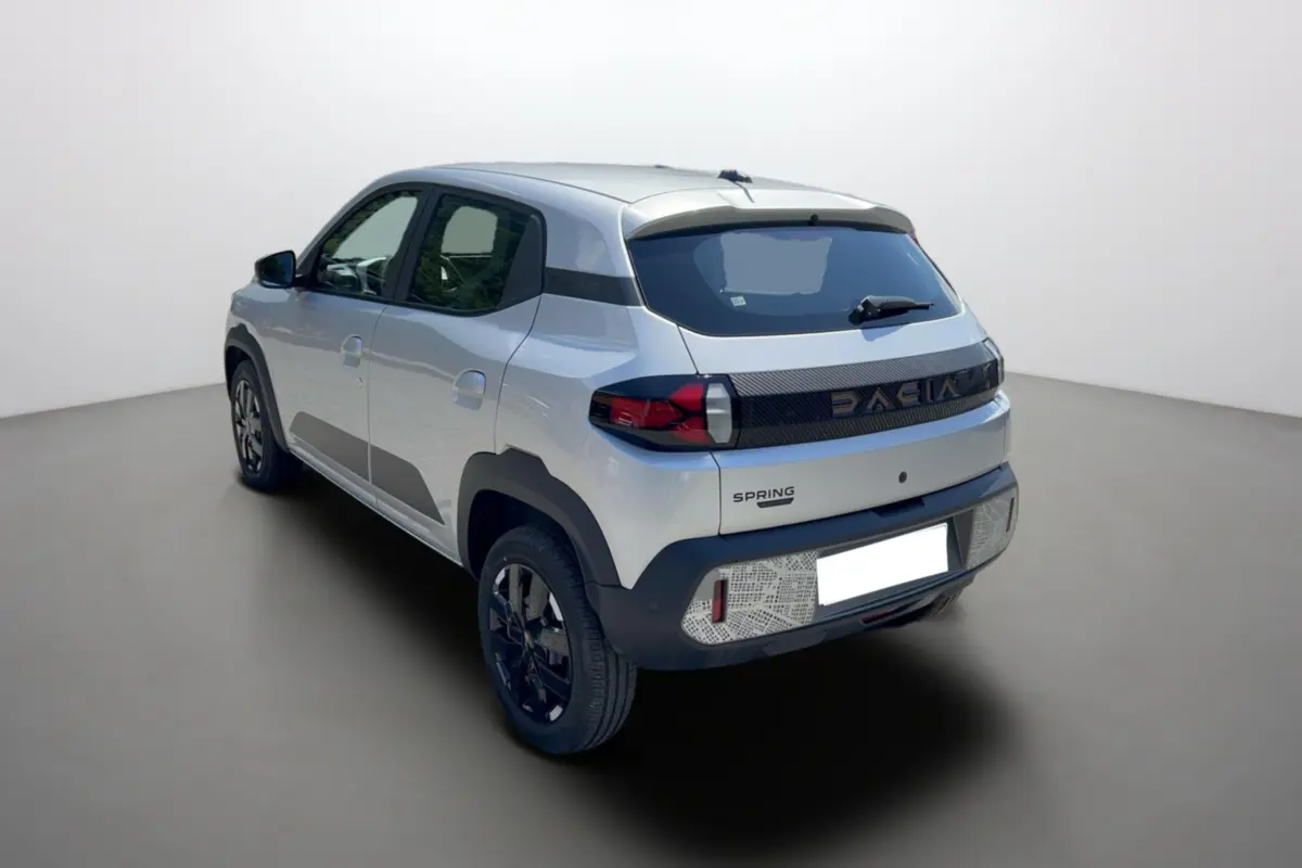 Vue 3/4 arrière droite d'une Dacia Spring gris éclair avec bande noire distinctive et jantes noires.