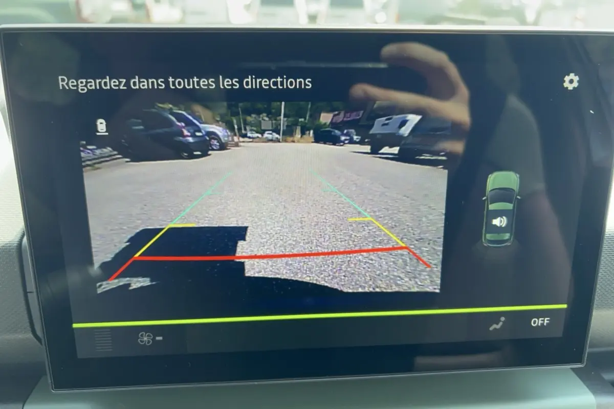 Écran de caméra de recul du Dacia Spring électrique 65 Extreme montrant la vue arrière avec lignes de guidage colorées.
