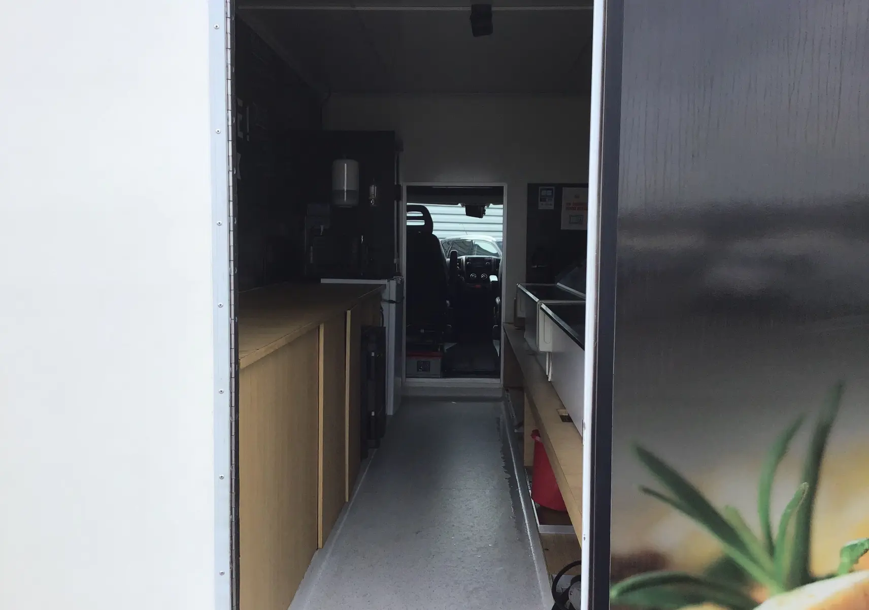 Vue intérieure en perspective du food truck gris graphito Citroën Jumper, montrant l'aménagement avec plan de travail et vitrines réfrigérées.