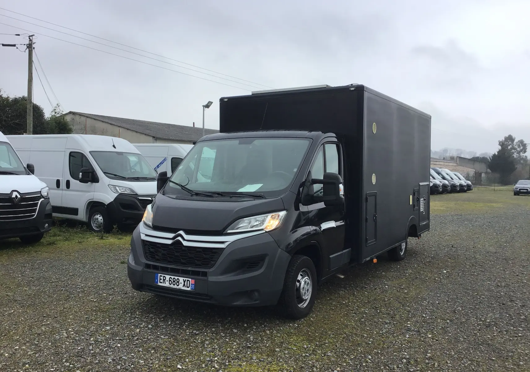 Citroën Jumper Planche cabine gris graphite vu 3/4 avant droit sur parking avec caisse magasin noire.