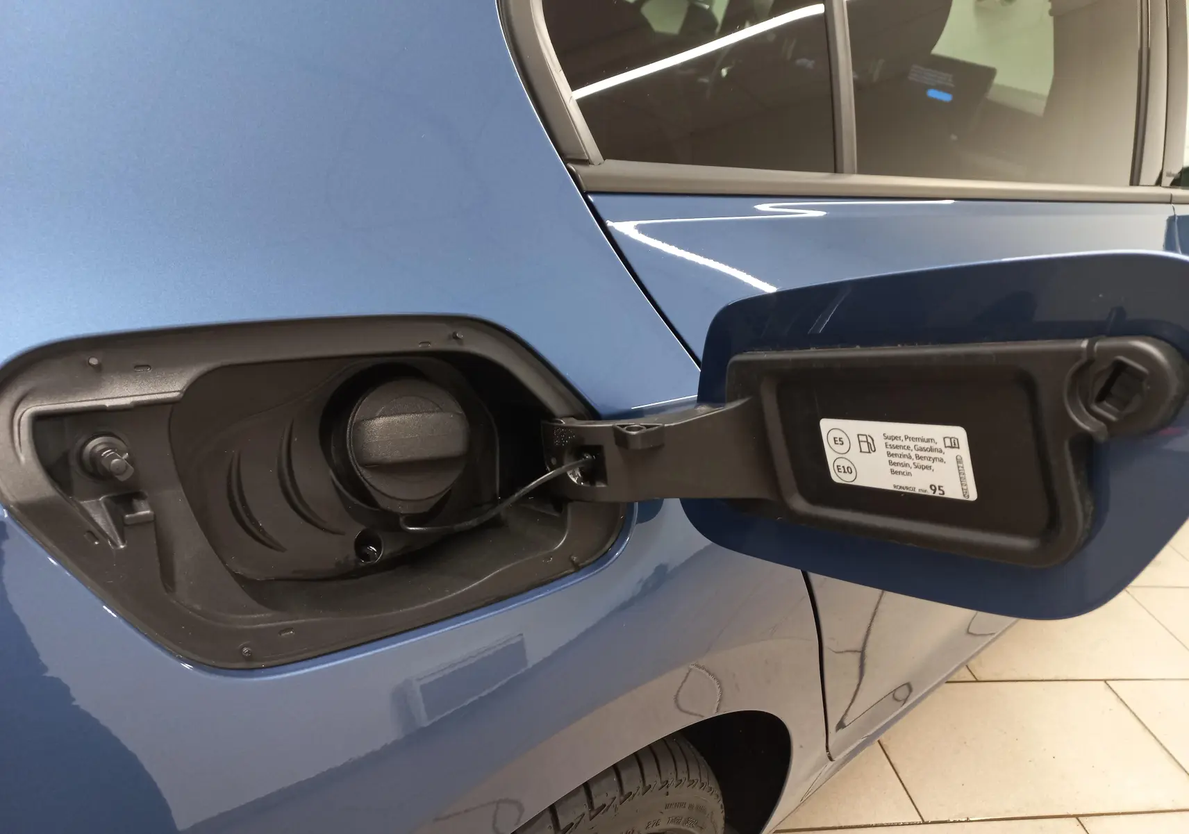 Bouchon de réservoir essence ouvert sur le côté gauche d'une Volkswagen Golf Bleu Anemone avec peinture métallisée.