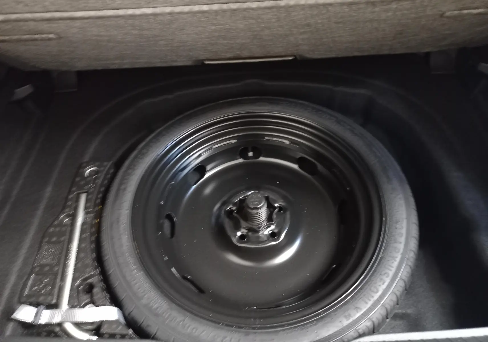 Roue de secours noire montée sur jante acier dans le coffre d'une Volkswagen Golf Bleu Anemone 2025.