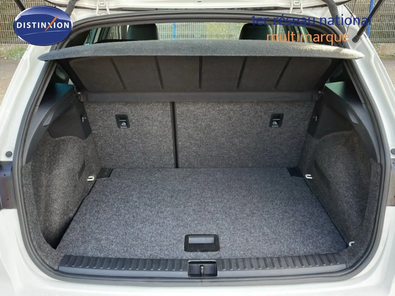 Coffre ouvert vu de l'arrière d'un SEAT Arona blanc avec toit noir, montrant un espace de chargement propre et vide.