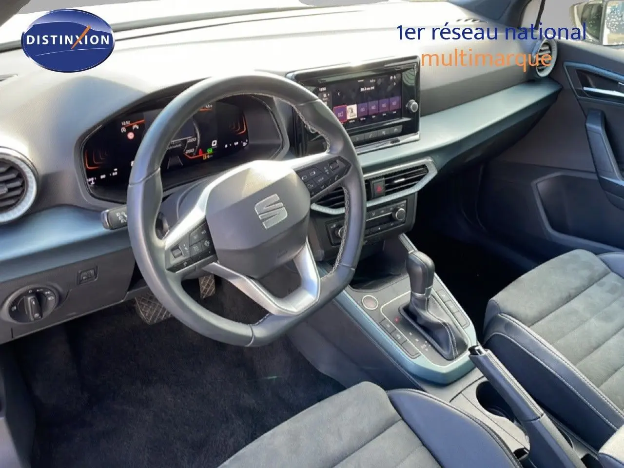 Vue intérieure du poste de conduite du SEAT Arona 2025, volant cuir multifonction et console centrale avec boîte automatique.