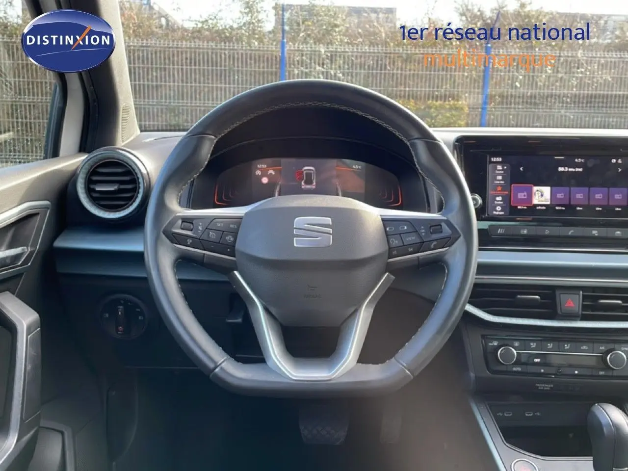 Vue intérieure centrée sur le volant cuir du SEAT Arona 2025 avec tableau de bord numérique et écran tactile.