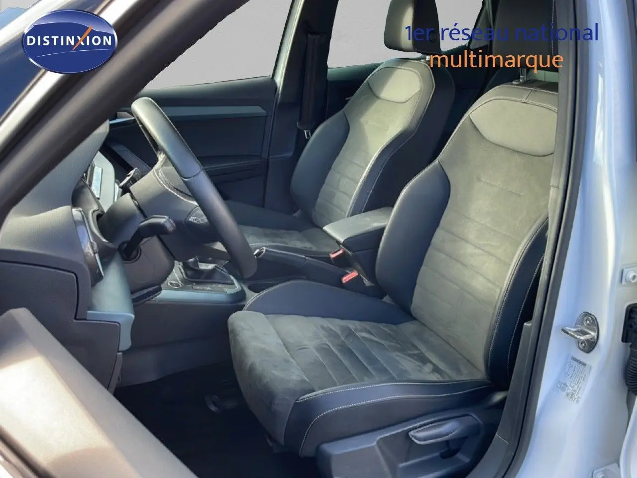 Vue intérieure côté conducteur du SEAT Arona blanc, mettant en valeur les sièges en cuir et alcantara gris foncé.