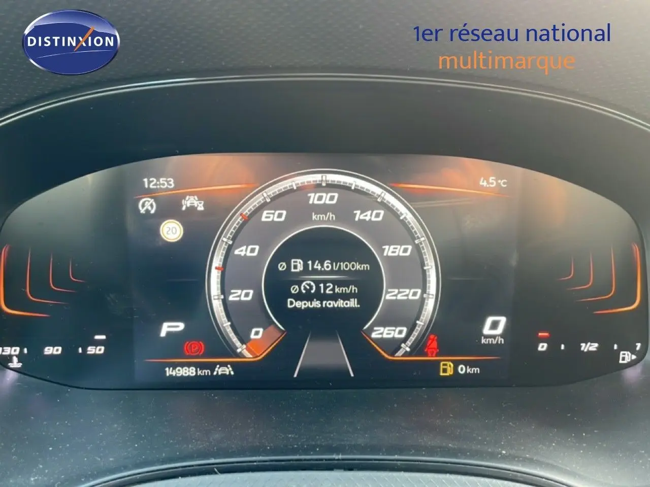 Vue rapprochée du tableau de bord numérique du SEAT Arona 2025, affichage de vitesse et consommation, ambiance orange.