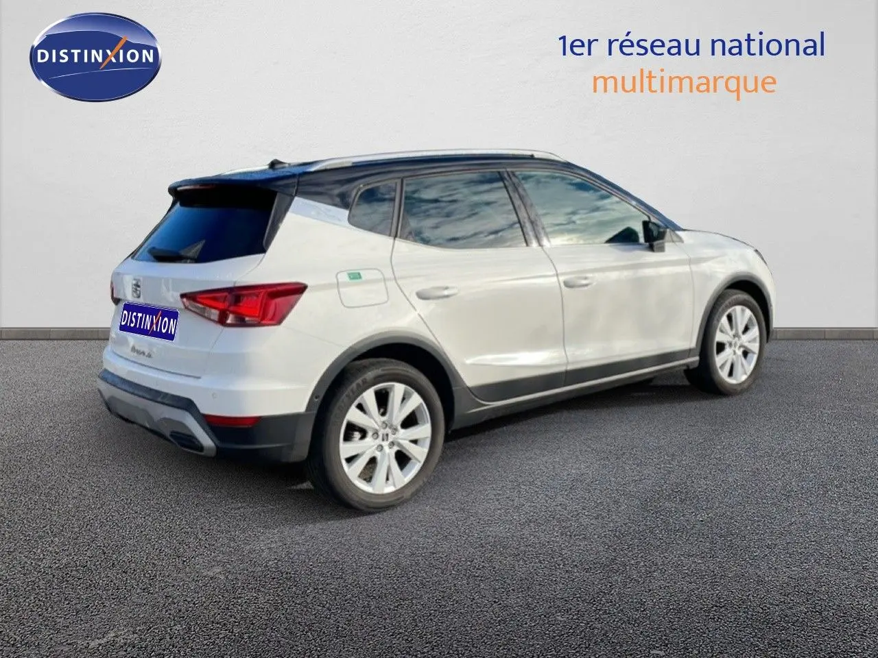 Vue 3/4 arrière droite d'un SEAT Arona blanc à toit noir, avec jantes alliage et vitres teintées.