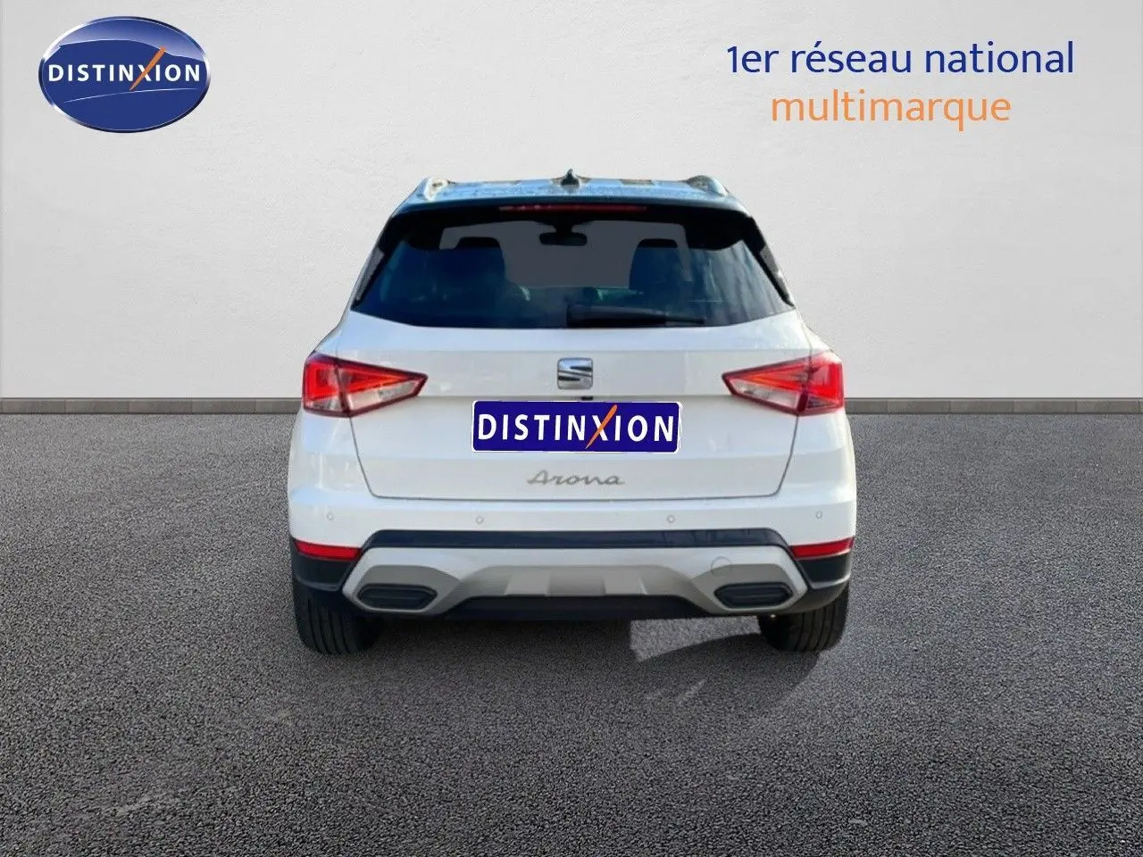 Vue arrière d’un SEAT Arona blanc avec toit noir, montrant ses feux arrière et double sortie d’échappement.