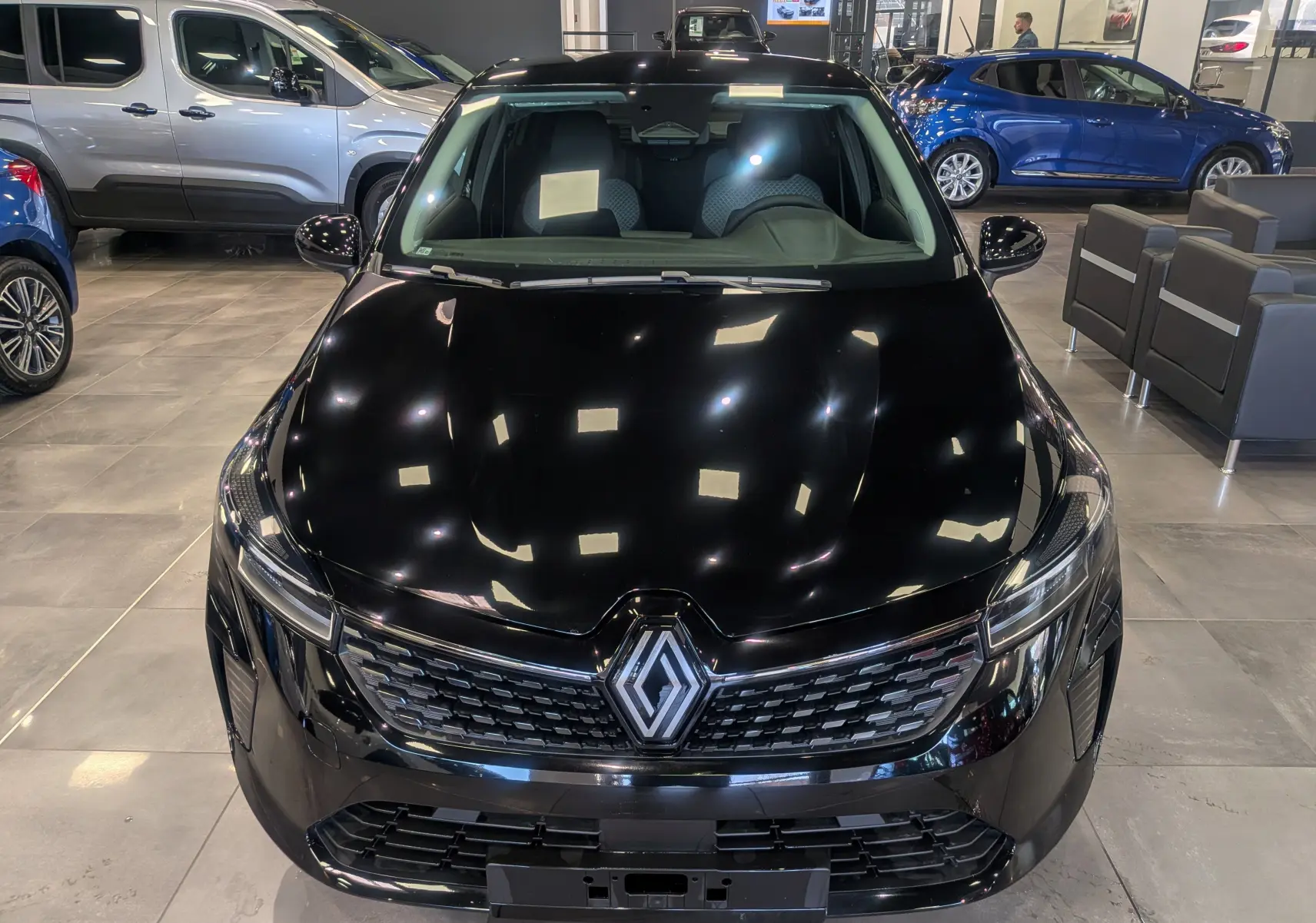 Vue avant d'une Renault Clio V noire 2025 en concession, mettant en valeur sa calandre et ses phares LED modernes.