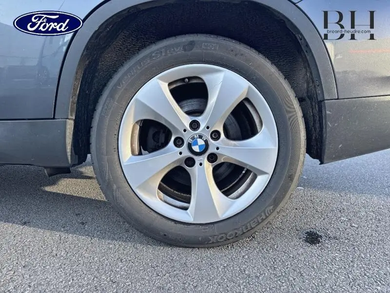 Gros plan sur la roue avant gauche avec jante alu 17 pouces du BMW X1 Mineralgrau, soulignant le logo BMW au centre.