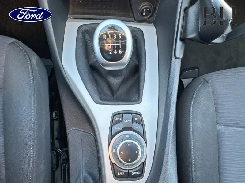 Vue rapprochée du levier de vitesses manuel et du contrôleur multimédia central d’un BMW X1 Mineralgrau 2013.