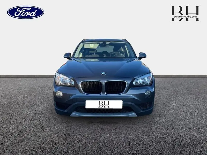 Vue frontale d'un BMW X1 sDrive20d 2013 en Mineralgrau avec calandre double haricot et phares halogènes.