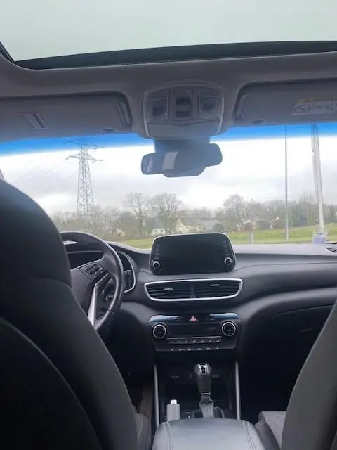Vue intérieure avant du Hyundai Tucson noir 2019, montrant tableau de bord, écran tactile et volant côté gauche.