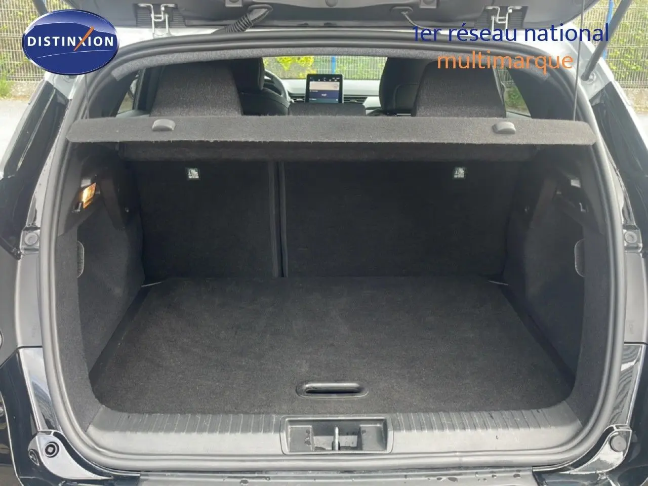 Coffre ouvert vu de l'arrière d'un Renault Captur noir étoile métal avec intérieur gris noir, montrant l'espace de chargement.