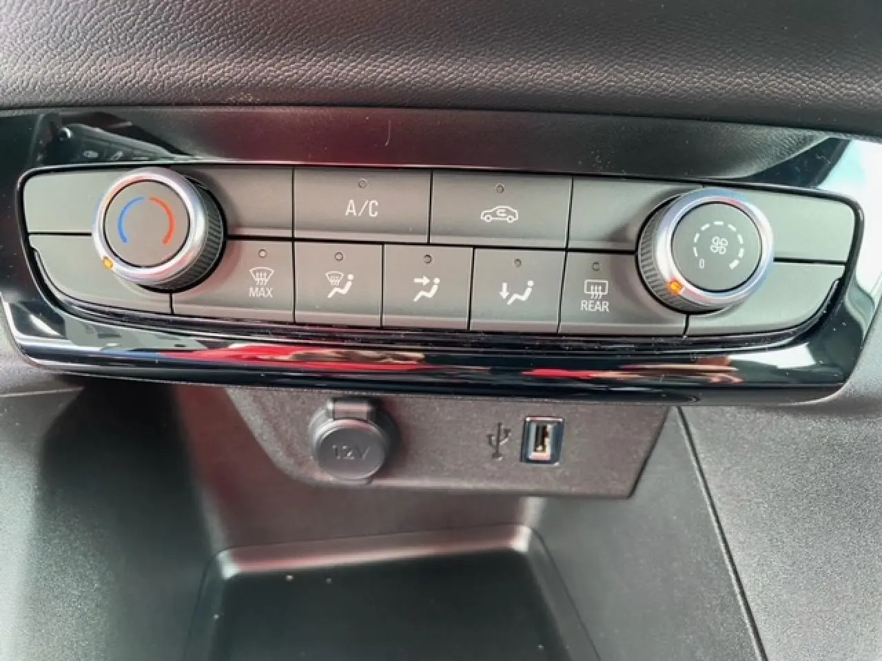 Gros plan sur la commande de climatisation manuelle et prises USB et 12V de l’Opel Corsa gris Magnetic 2022.