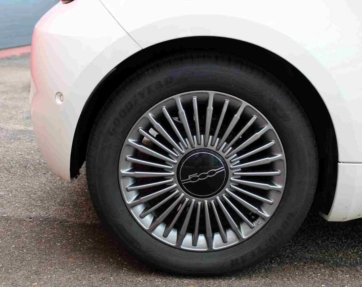 Gros plan sur la roue arrière droite blanche de la FIAT 500 électrique 2023 avec jante argentée à rayons fins et logo central 500.