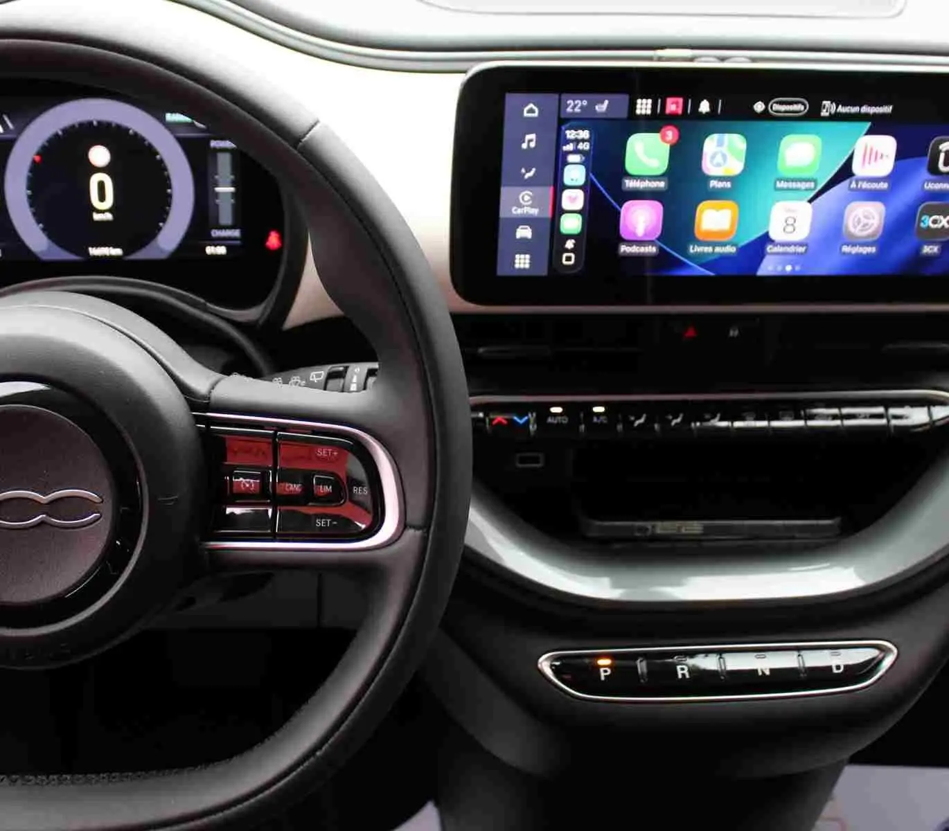 Vue intérieure du tableau de bord de la Fiat 500 électrique 2023, avec écran tactile CarPlay et volant multifonction noir.