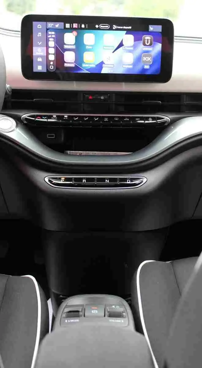 Vue intérieure centrée sur la console et l’écran tactile de la Fiat 500 électrique 2023, sièges noirs avec surpiqûres blanches.