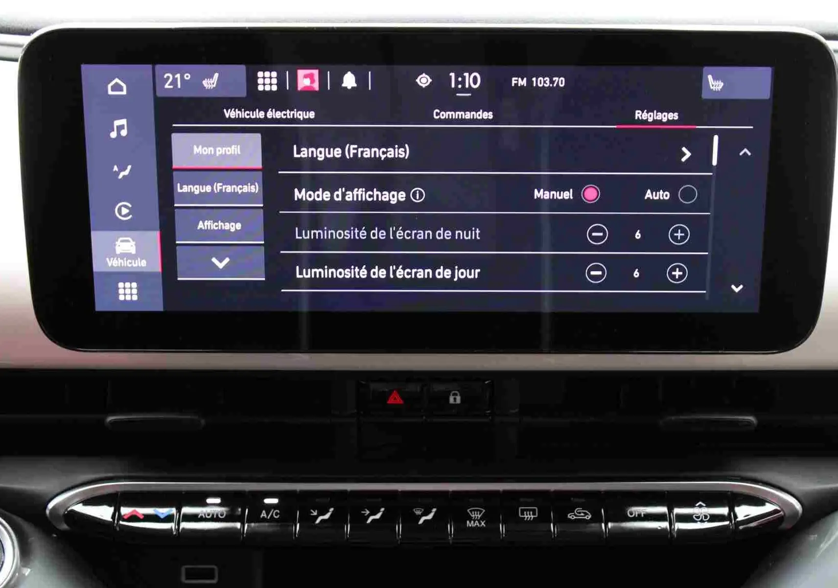 Écran tactile central de la Fiat 500 électrique 2023 montrant les réglages de langue et luminosité, intérieur noir.