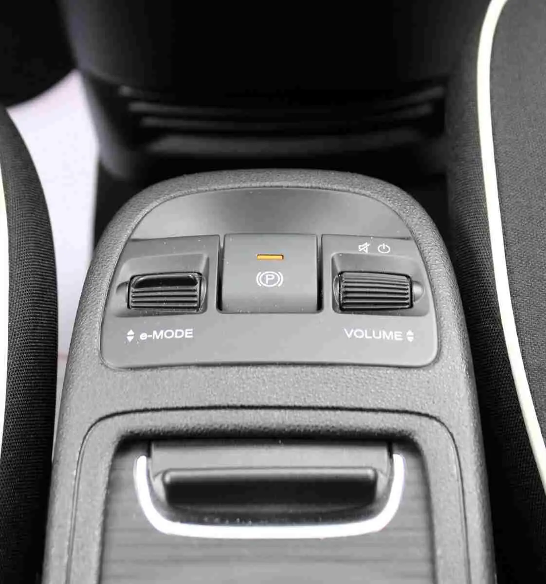 Gros plan sur la console centrale de la Fiat 500 électrique blanche, avec commandes e-Mode, frein à main électronique et réglage du volume.