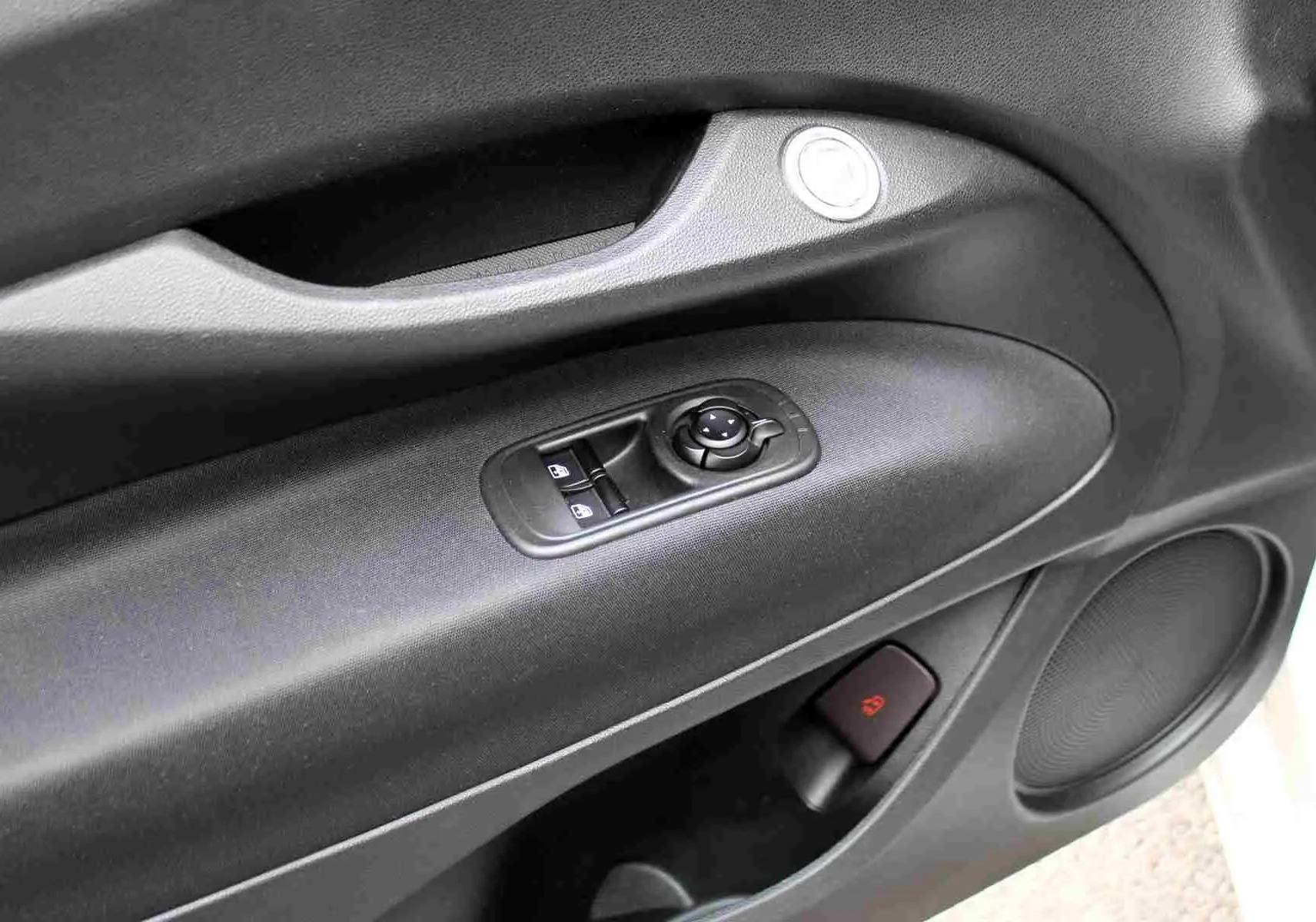 Gros plan sur la porte côté conducteur de la FIAT 500 électrique blanche, montrant les commandes de vitres et le haut-parleur intégré.