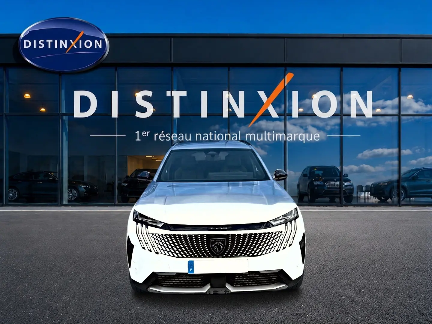 Vue frontale d'un Peugeot 5008 blanc garé devant une vitrine Distinxion avec calandre noire distinctive.