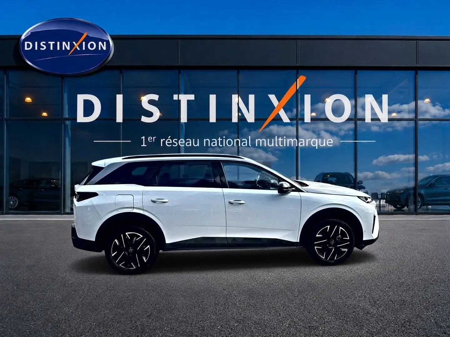 Peugeot 5008 Hybrid 145 allure blanc vue de profil côté gauche devant une vitrine avec logo Distinxion.