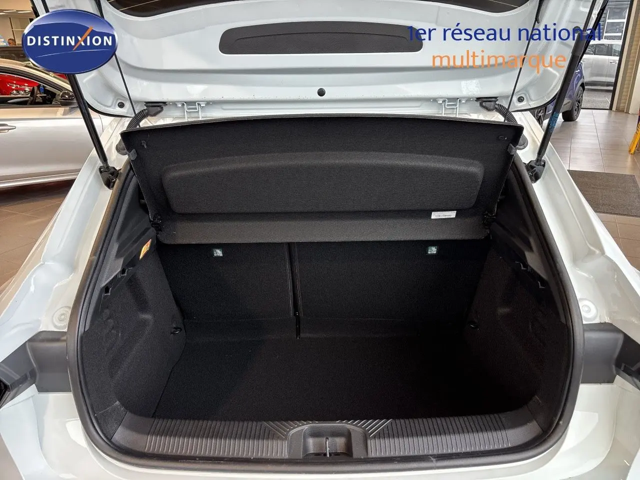 Coffre ouvert vu de l'arrière d'une Renault Clio VI TCE 115ch Techno blanc glacier, intérieur noir spacieux.