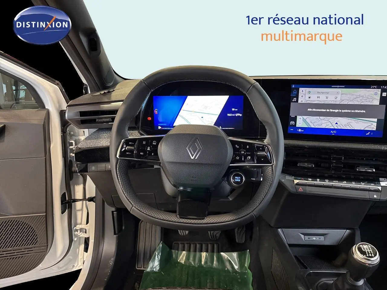 Vue intérieure centrée sur le volant Renault d’une Clio blanche 2026, avec tableau de bord numérique et boîte manuelle visible.