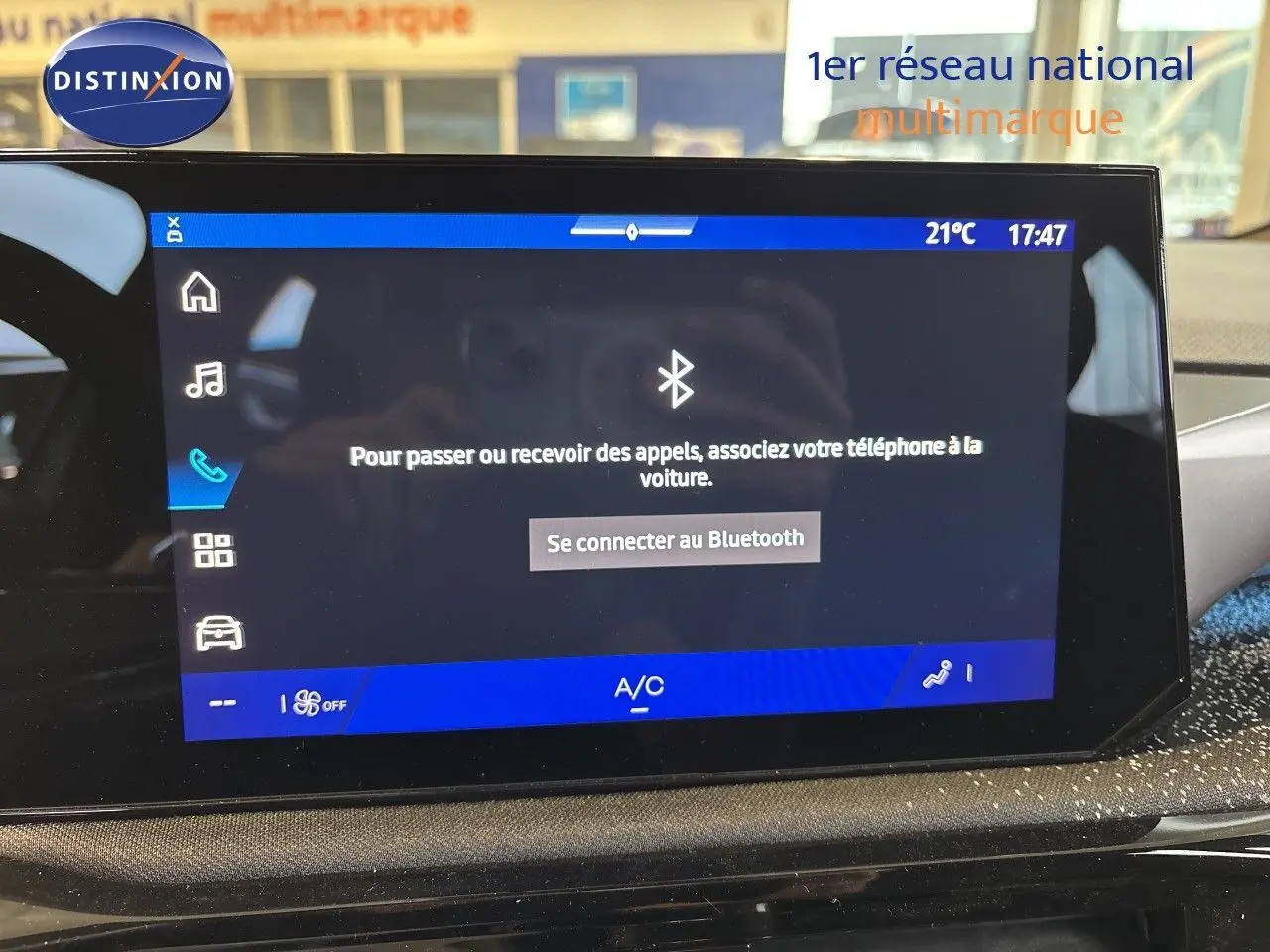 Écran tactile central de la Renault Clio VI blanc glacier, affichant la connexion Bluetooth et la climatisation à 21°C.