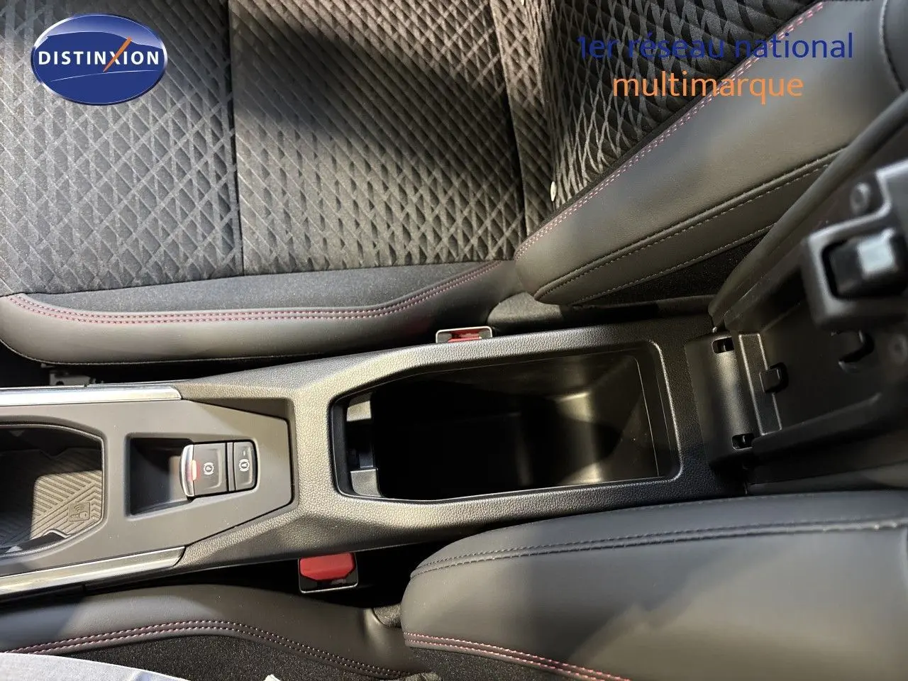 Vue rapprochée de la console centrale et des sièges en tissu noir avec surpiqûres rouges de la Renault Clio VI blanc glacier.
