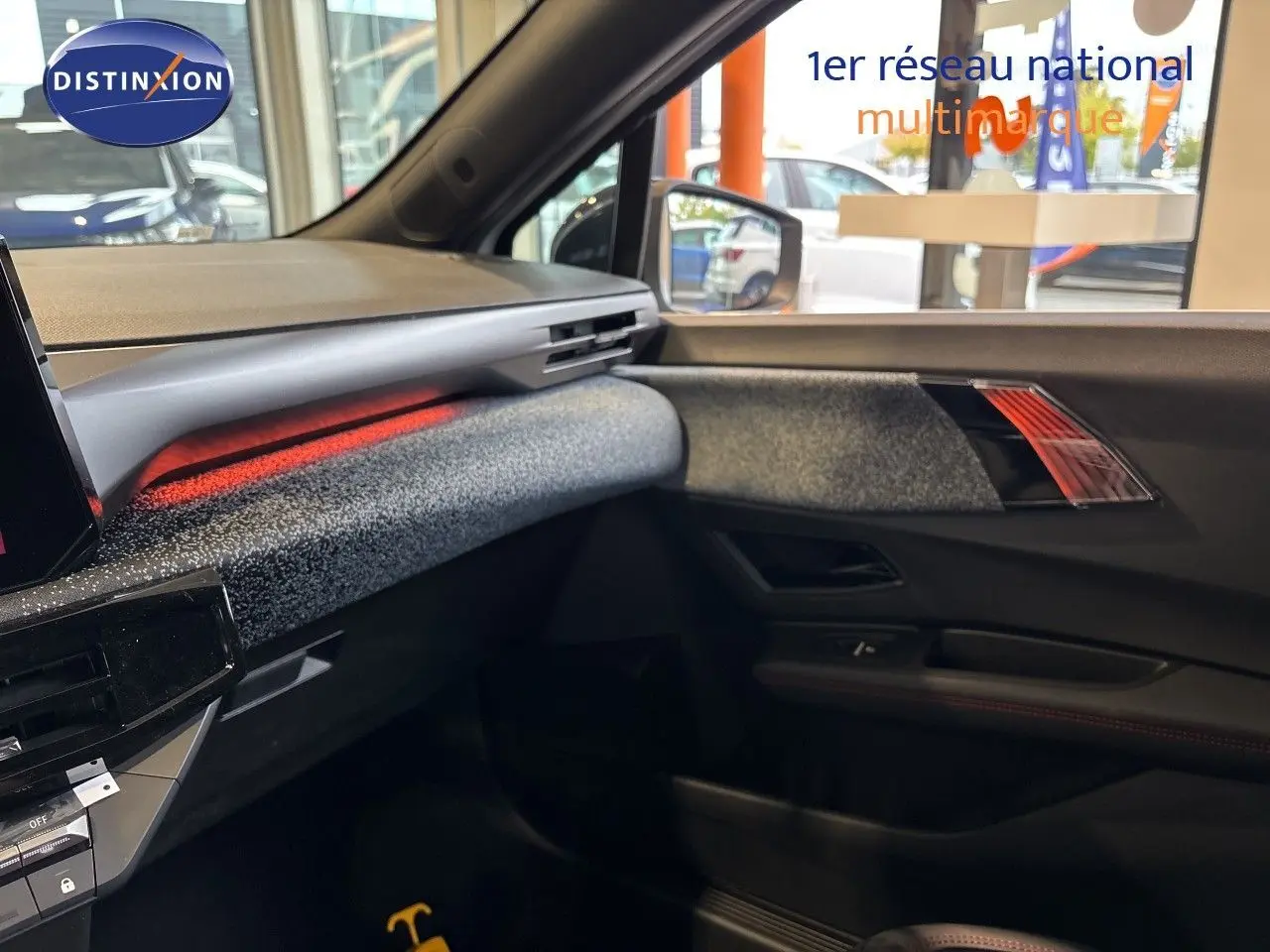 Vue intérieure côté passager de la Renault Clio VI TCe 115ch Techno 2026, ambiance noire avec éclairage d'ambiance rouge.