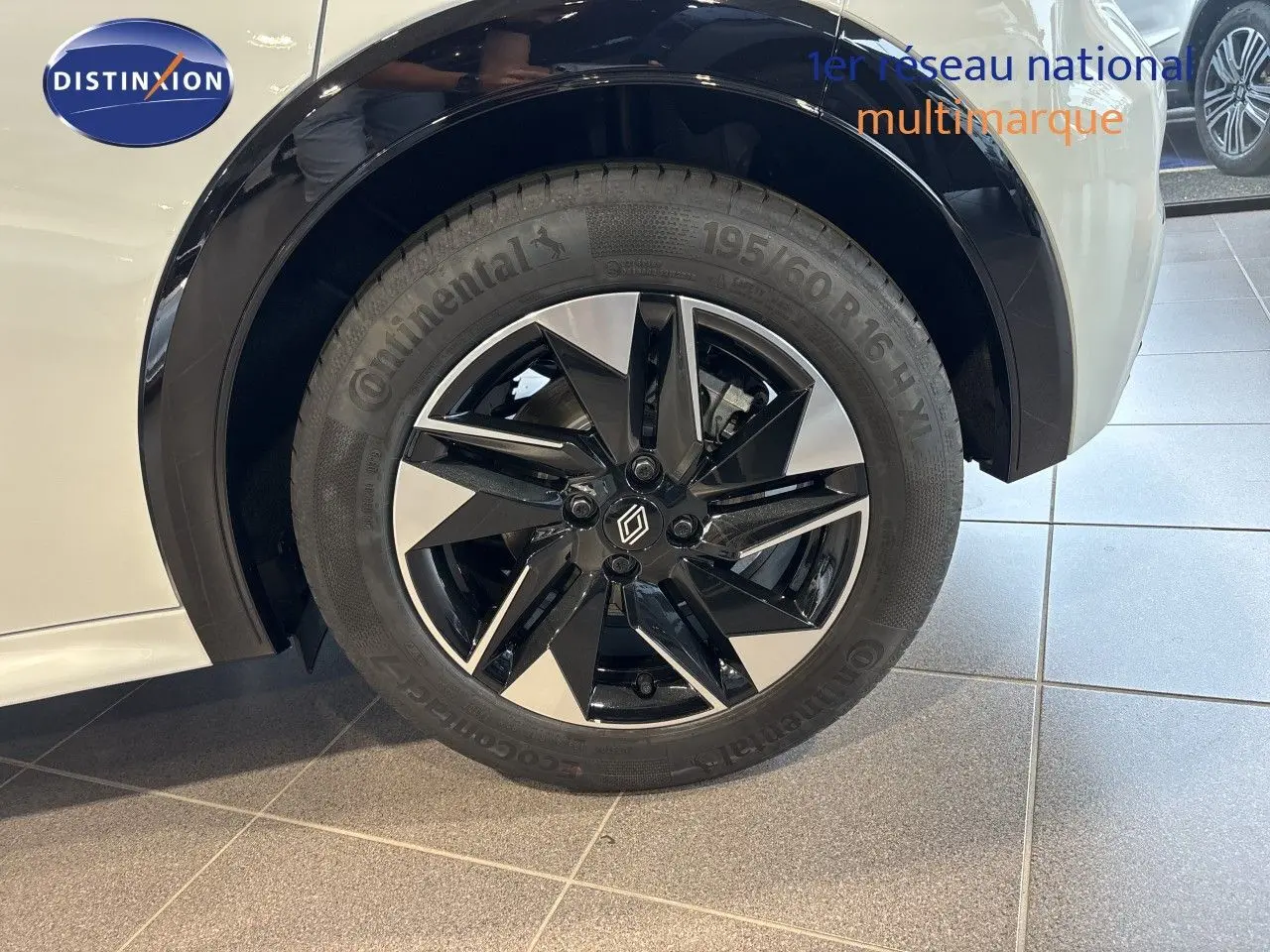 Gros plan sur la roue avant gauche de la Renault Clio blanc glacier avec jante alliage noir et argent.