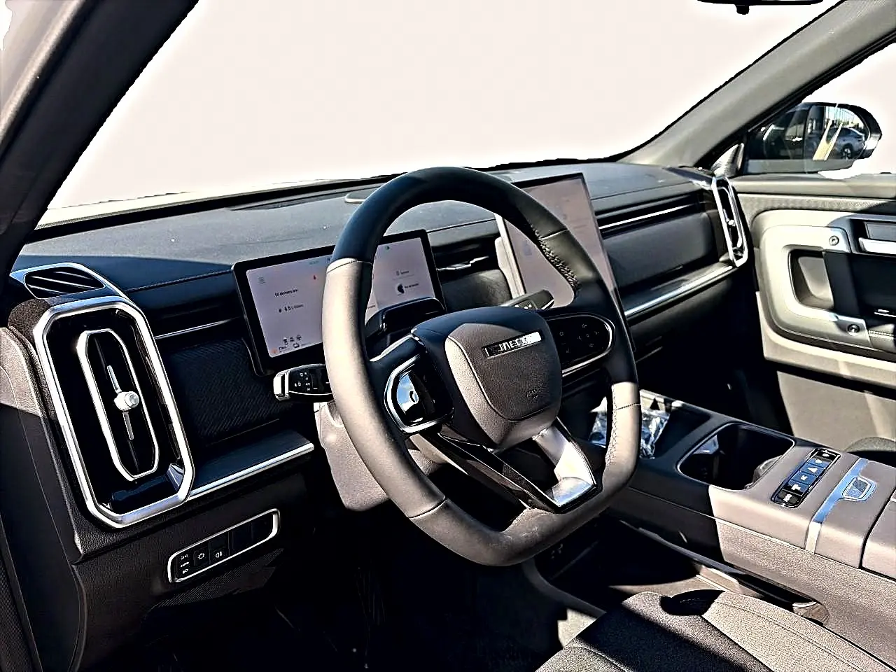 Vue intérieure côté conducteur du JAECOO J7 2026, volant multifonction noir et tableau de bord avec écrans tactiles.