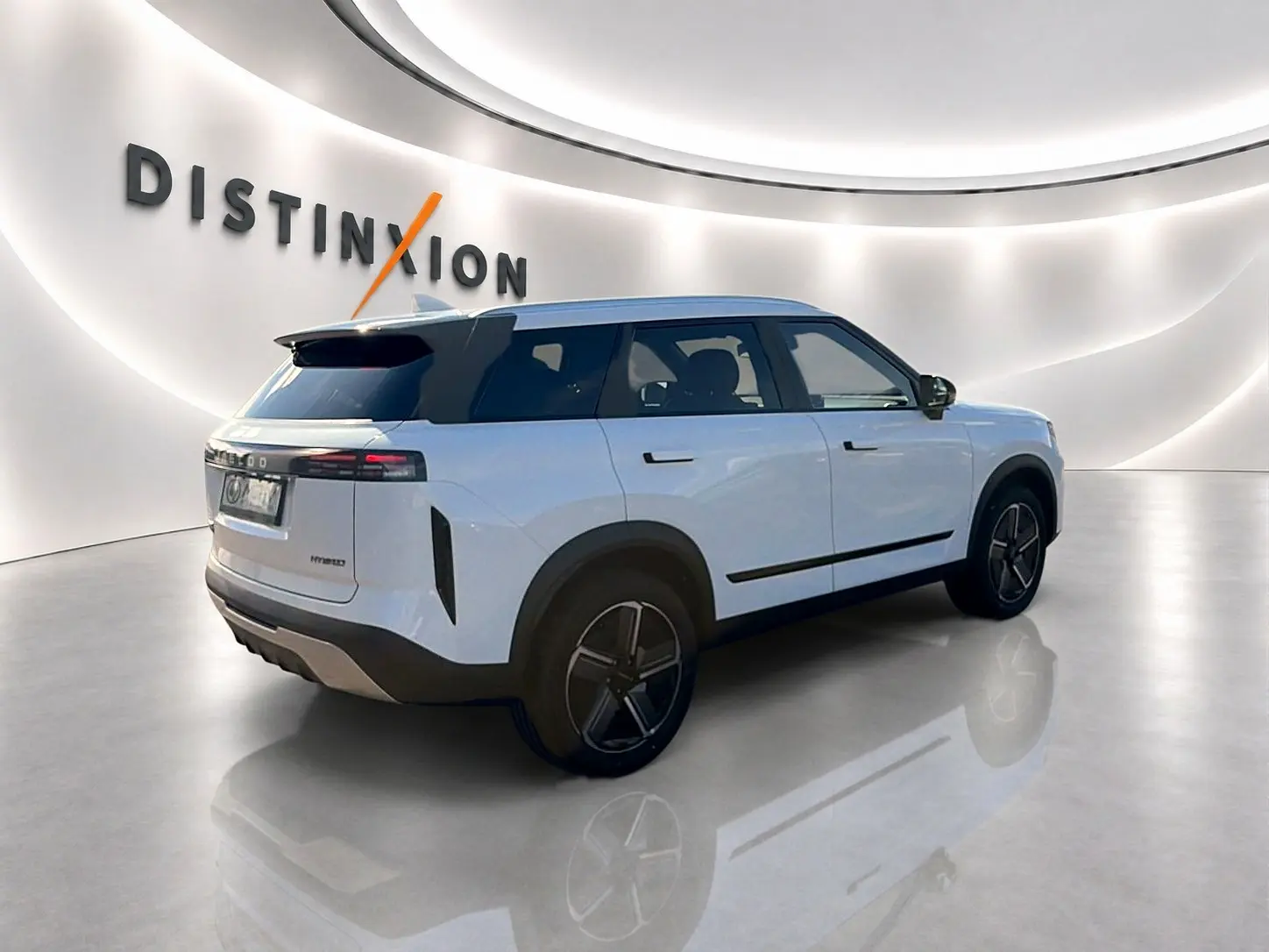 Vue 3/4 arrière droite du SUV JAECOO J7 blanc kaki avec toit noir et jantes alu distinctives dans un showroom.