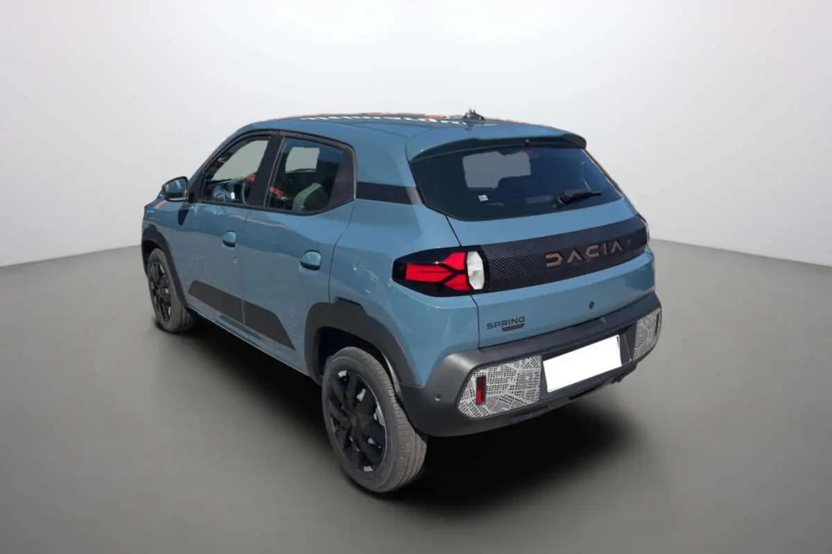 Vue 3/4 arrière droite d'une Dacia Spring électrique 65 Extrême bleu ardoise avec détails noirs et feux arrière LED.