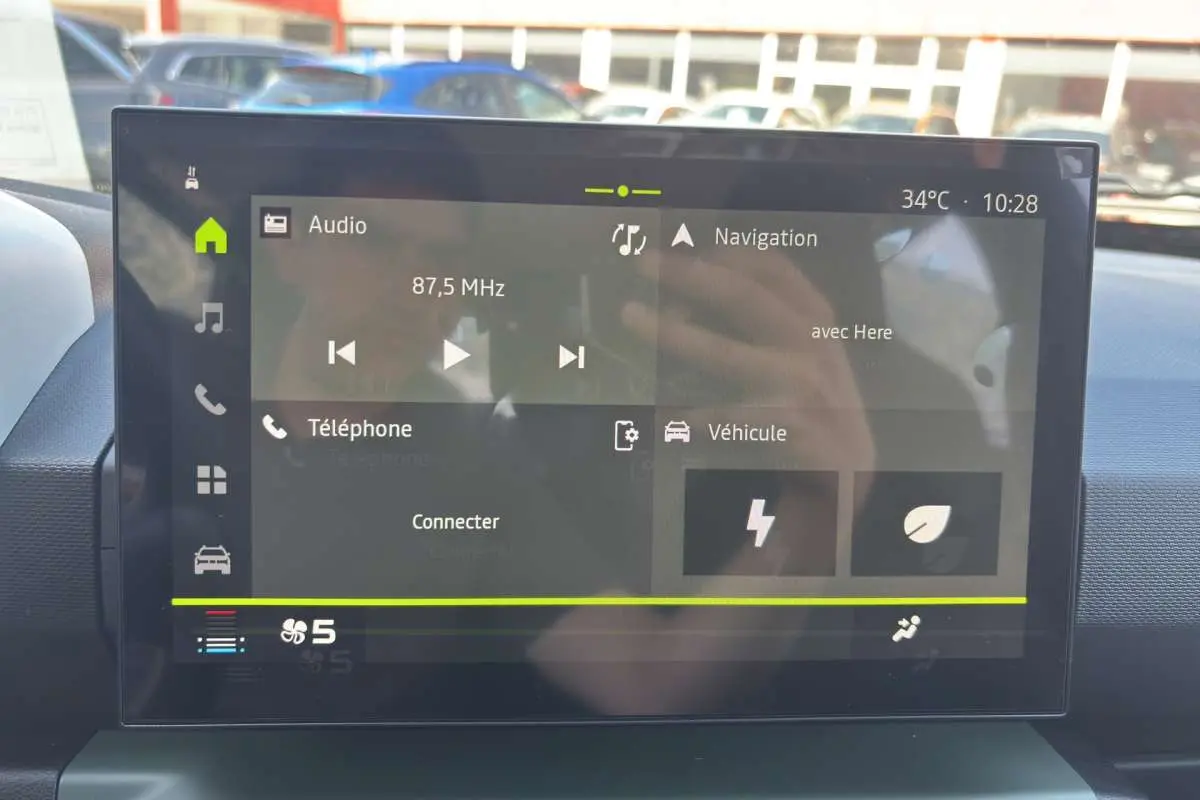 Écran tactile central du tableau de bord du Dacia Spring 2026 affichant radio, navigation et options connectées.