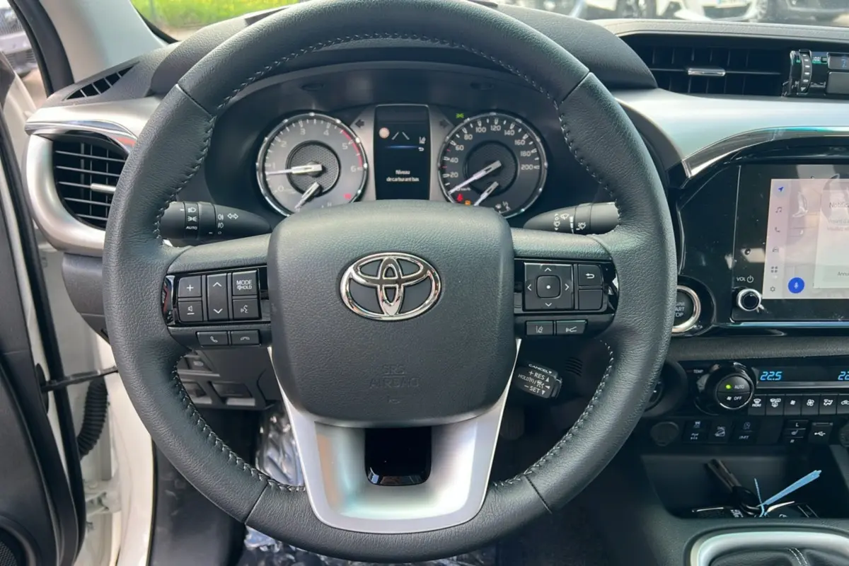 Vue rapprochée du volant et du tableau de bord du Toyota Hilux 2025, avec commandes intégrées et écran tactile.
