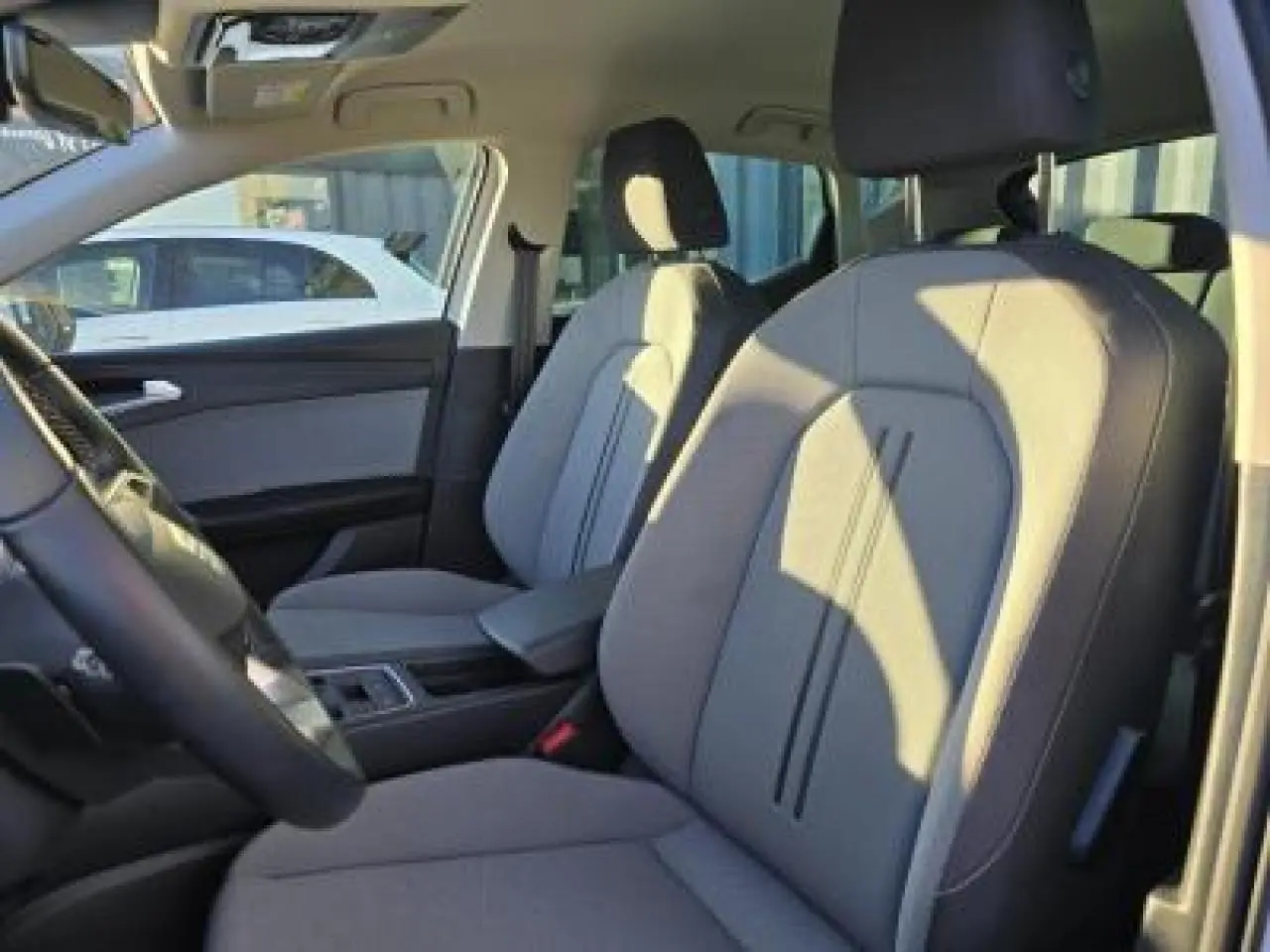 Intérieur de la SEAT LEON blanc, vue côté gauche sur les sièges avant gris avec accoudoir central.
