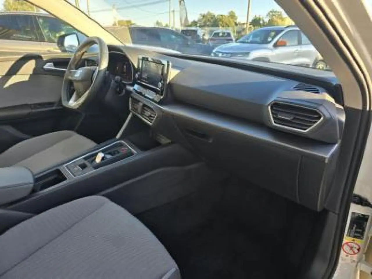 Intérieur de la SEAT LEON IV blanc, vue côté conducteur, tableau de bord moderne avec écran tactile central.