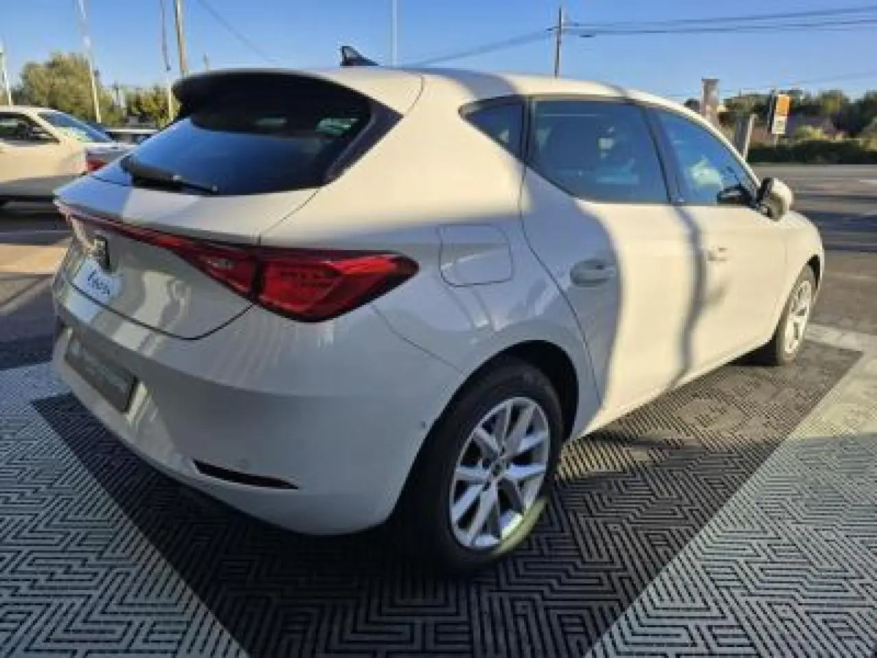 SEAT LEON blanc vue 3/4 arrière droit, jantes alliage 16 pouces, feux arrière LED et toit noir contrasté.