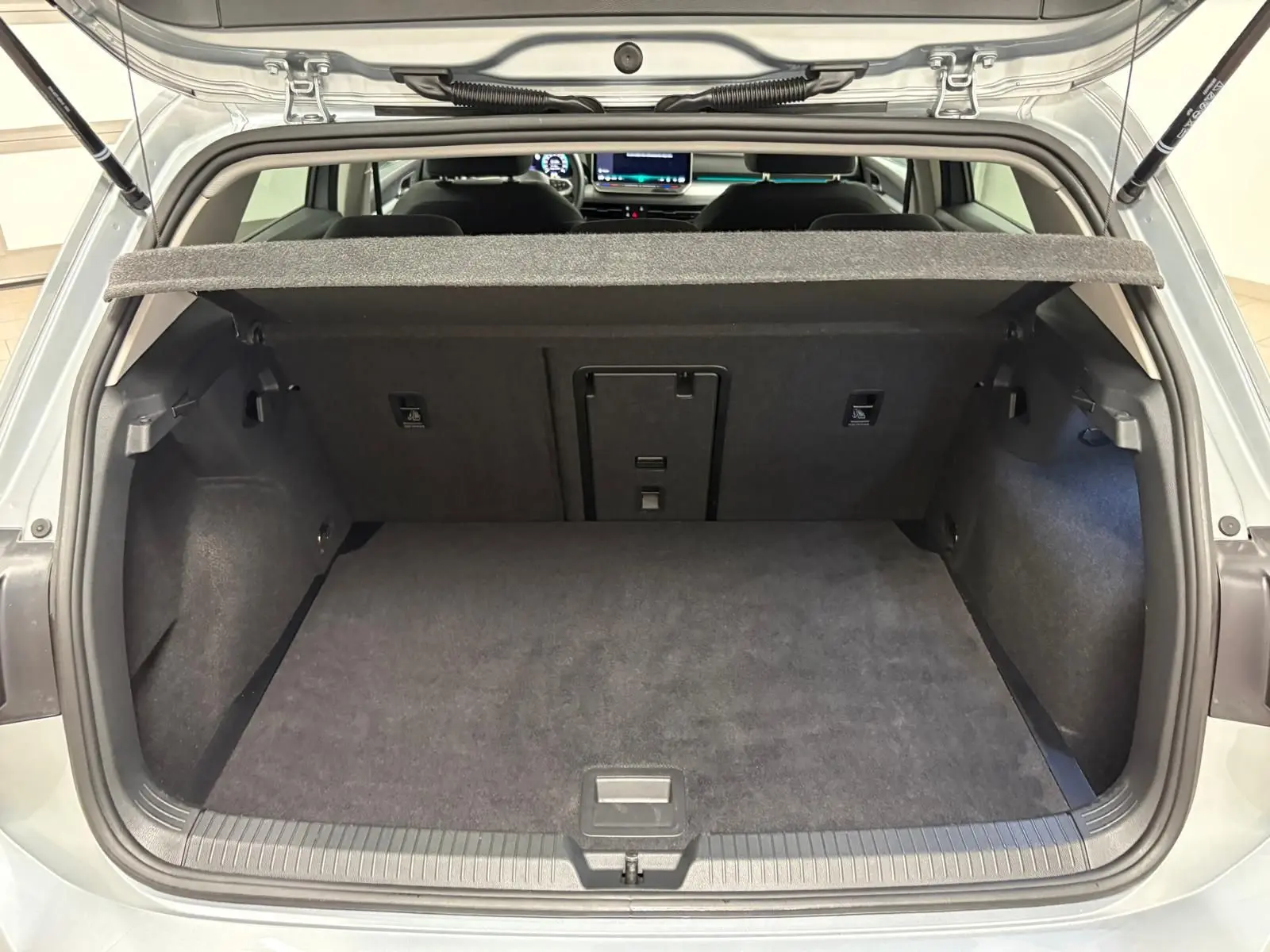 Vue arrière du coffre ouvert d'une Volkswagen Golf 1.5 TSI 116 BVM6 VW Edition en argent Dolomite, intérieur noir.