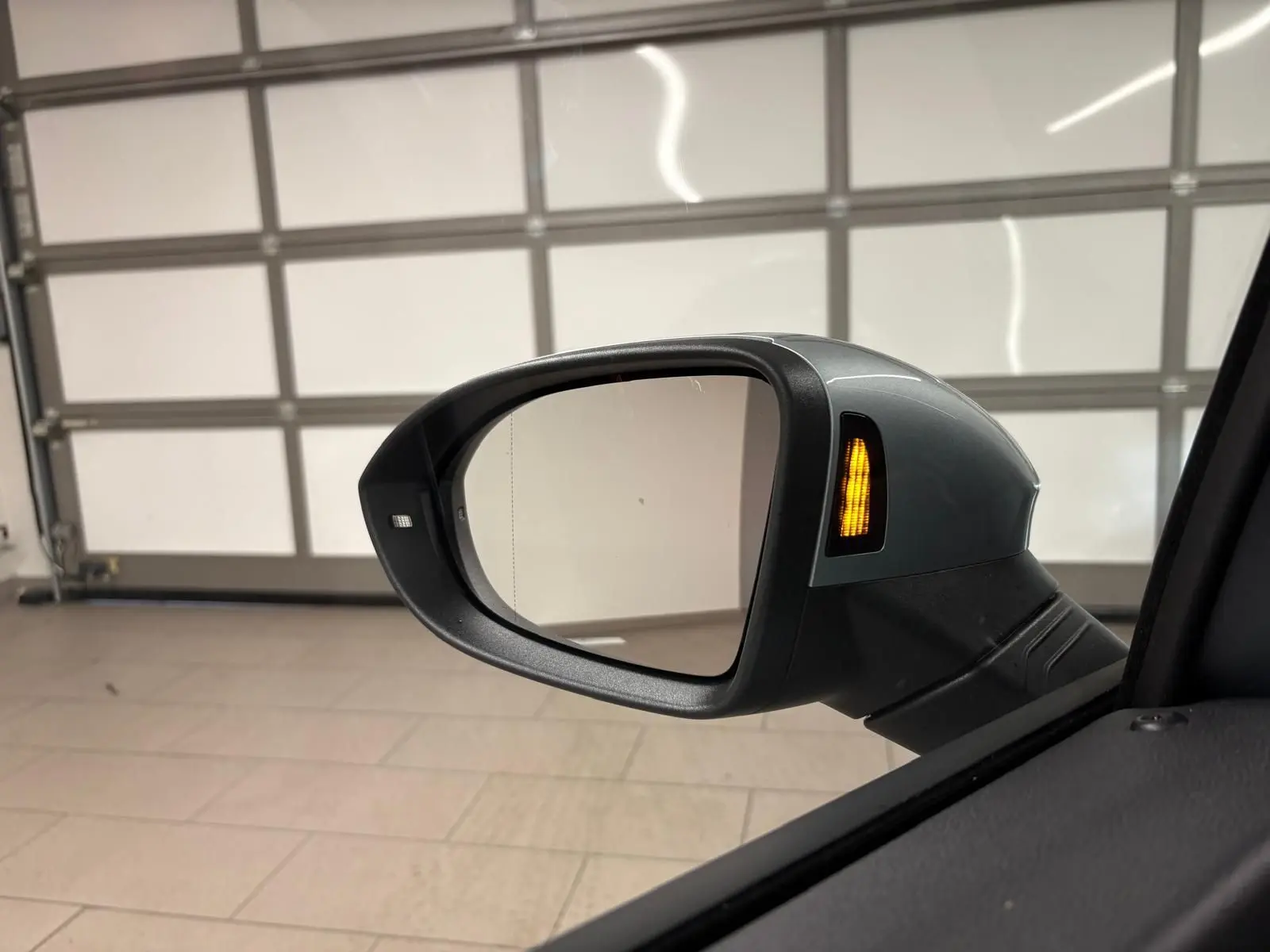 Rétroviseur extérieur côté gauche de la Volkswagen Golf 1.5 TSI argent Dolomite avec clignotant allumé.