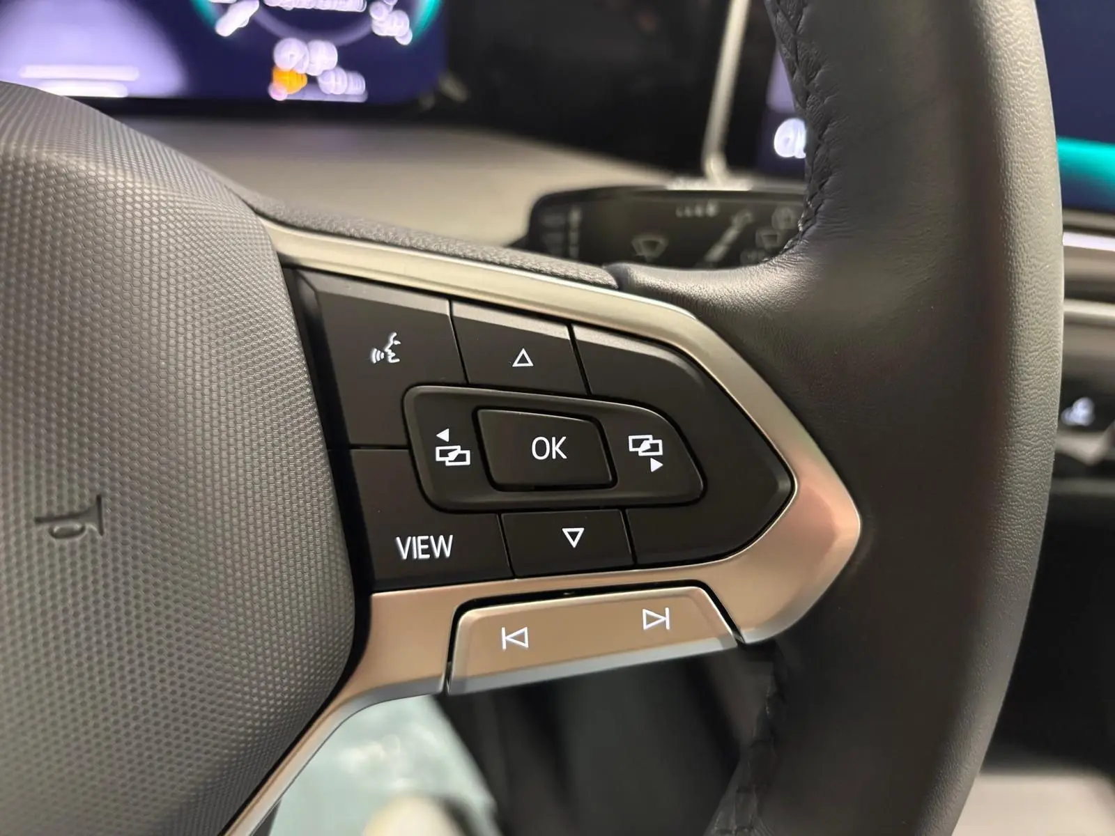 Gros plan sur les commandes multifonctions du volant en cuir noir de la Volkswagen Golf 1.5 TSI 2025.