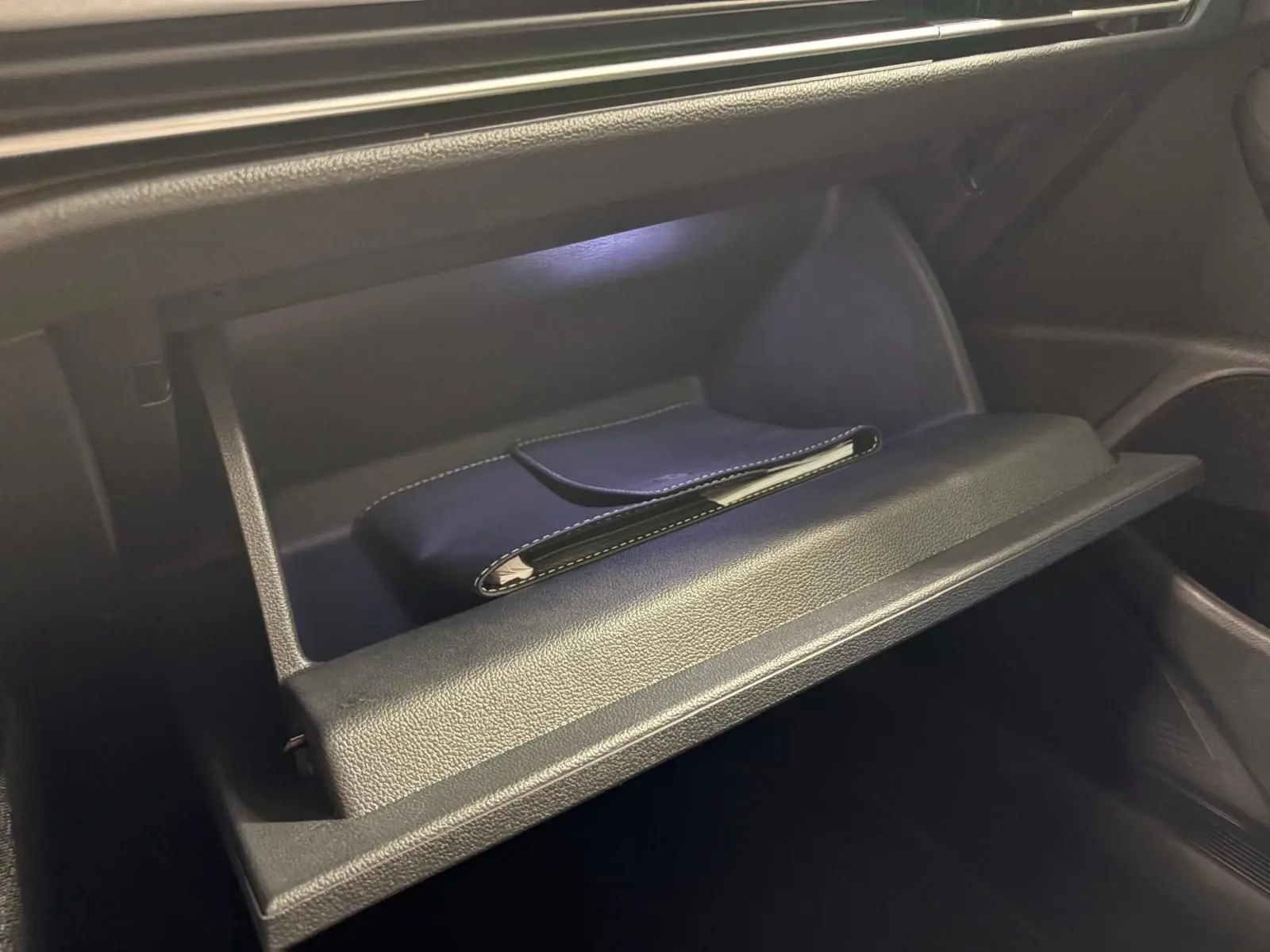 Gant de boîte à gants ouvert montrant un étui noir à l'intérieur d'une Volkswagen Golf 1.5 TSI 2025.