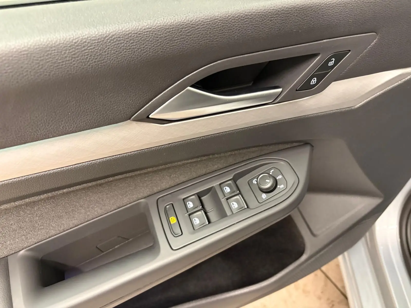 Gros plan sur la commande des vitres et des rétroviseurs côté conducteur de la Volkswagen Golf 1.5 TSI 2025 argent Dolomite.