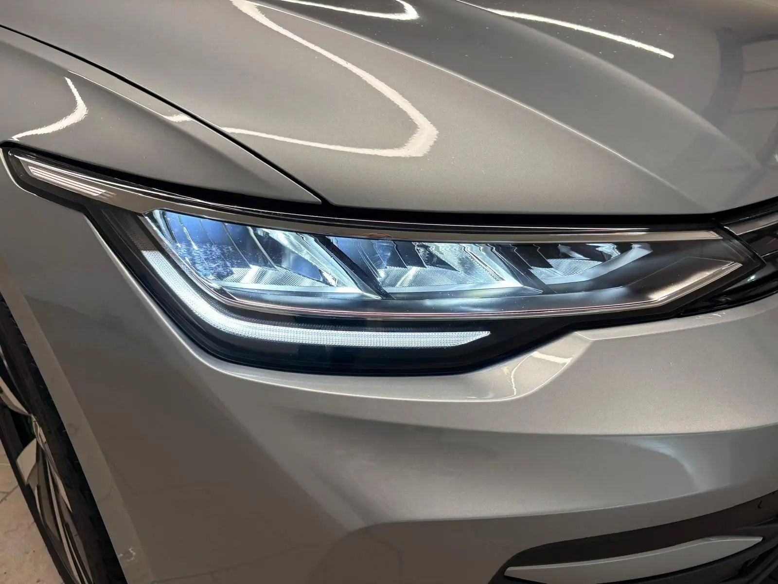 Gros plan sur le phare avant droit d'une Volkswagen Golf 1.5 TSI 2025 en Argent Dolomite métallisé.