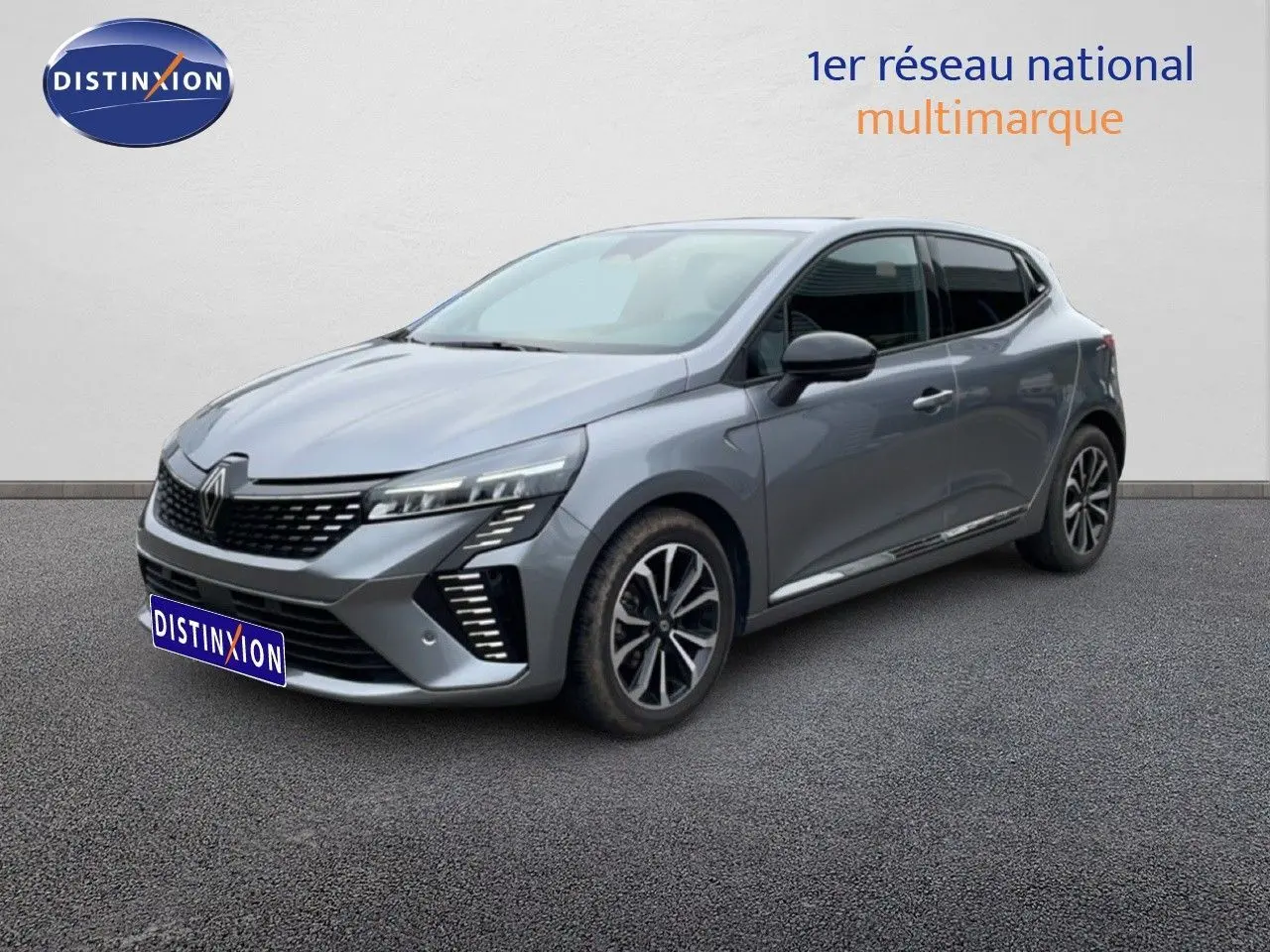 Renault Clio 2025 gris schiste métal en 3/4 avant droit, avec calandre noire et feux LED distinctifs.